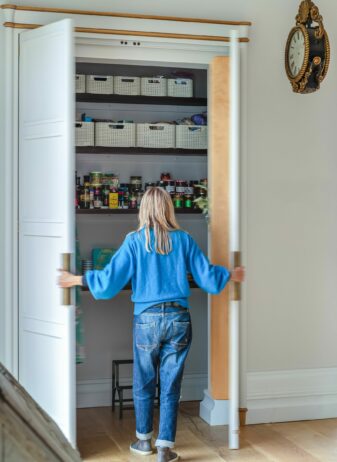 A bespoke kitchen larder cabinet being opened by a woman