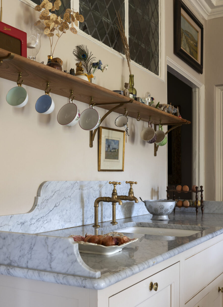 Open kitchen shelves with brass brackets sit above the sink area Open kitchen shelves with brass brackets sit above the sink area