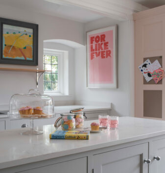 A combination of an oil painting and a striking print are used in this neutral kitchen to add a decorative element to the walls.