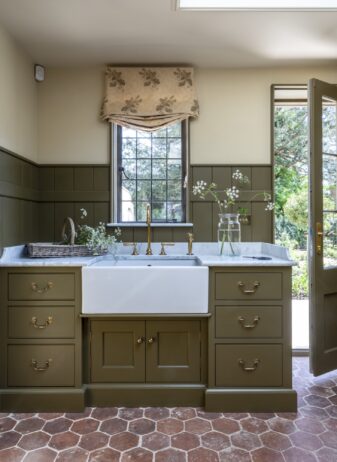 Modern Scullery with a Butler sink, stone floor and worktops and green hand painted cabinetry by the back door