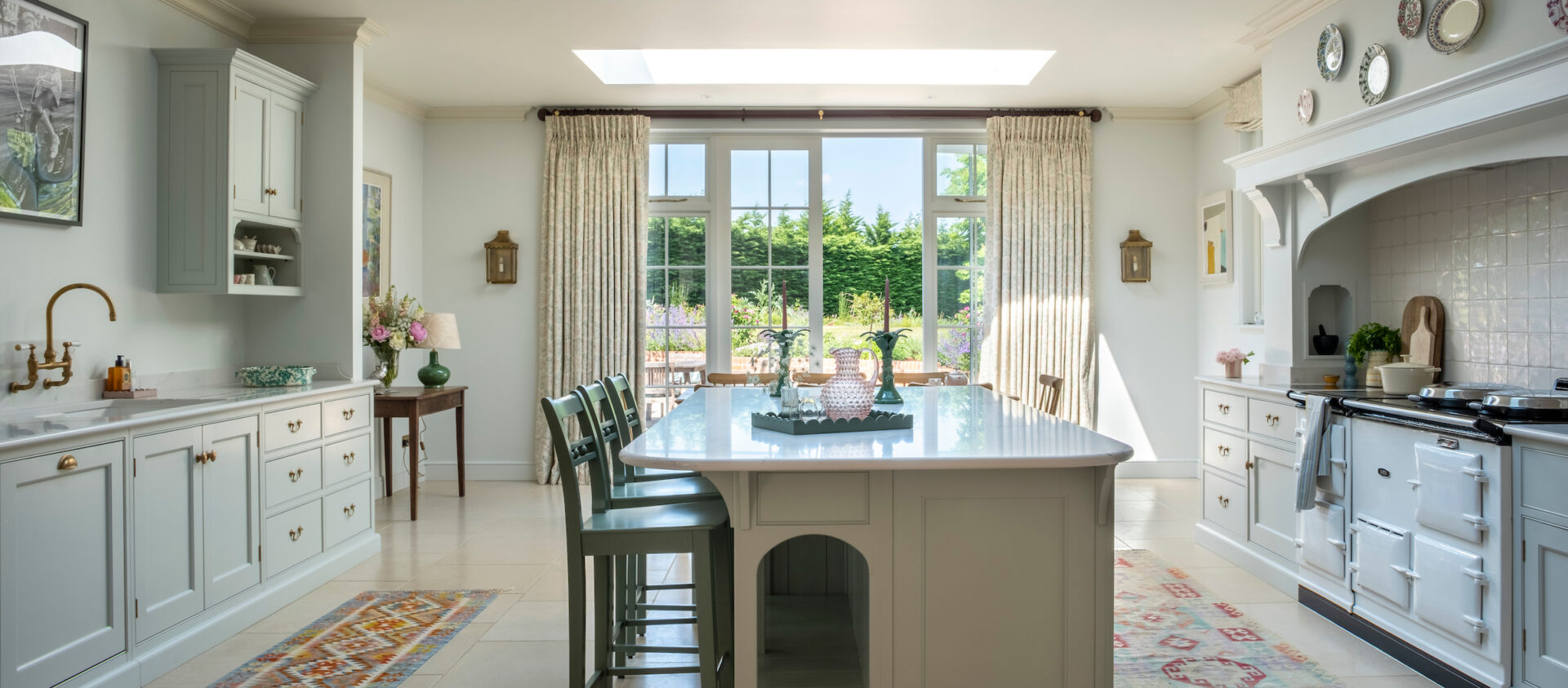 Wide view of a kitchen island with pale cabinetry on either side