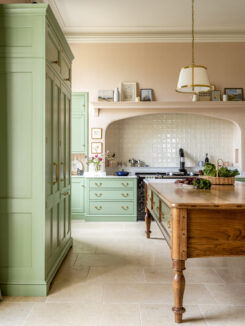 Green cabinets with plaster pink walls in a Georgian house kitchen