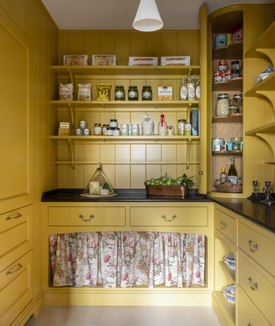 Yellow walk in kitchen pantry with curved corner cabinet and stone worktop
