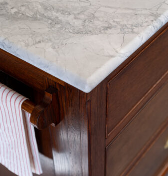 A bespoke wooden towel rail hangs at one end of the country farmhouse kitchen island