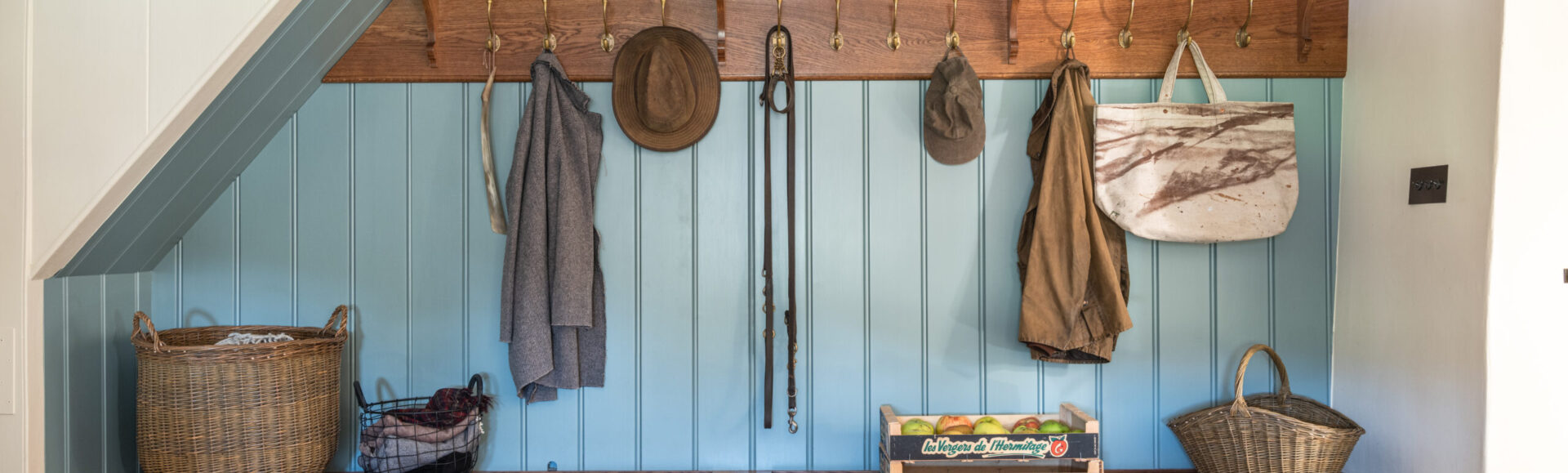 Under stairs bespoke boot room storage within the kitchen scullery with oak bench and blue panelled wall