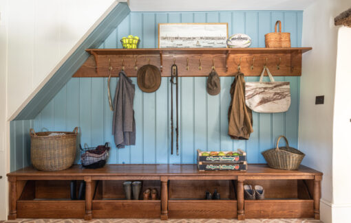 Under stairs bespoke boot room storage within the kitchen scullery with oak bench and blue panelled wall
