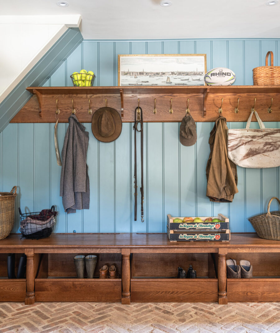 Under stairs bespoke boot room storage within the kitchen scullery with oak bench and blue panelled wall Under stairs bespoke boot room storage within the kitchen scullery with oak bench and blue panelled wall