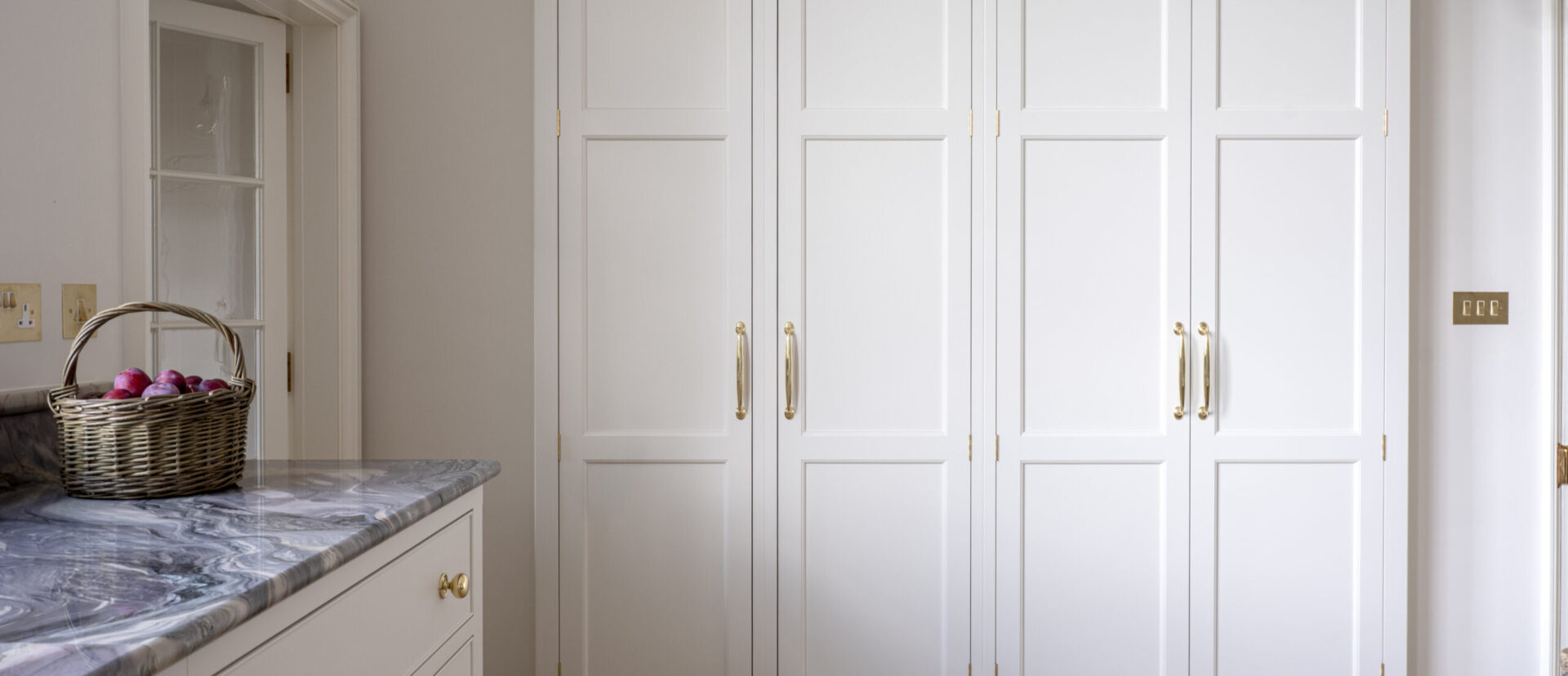 A large storage cupboard recessed into the wall in a kitchen