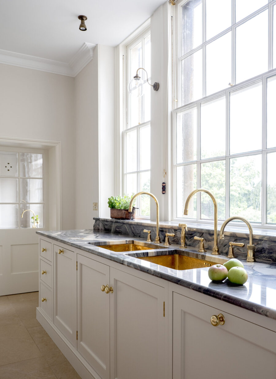 A sink run with gold sinks sits on a marble worktop in a Kitchen for a Regency Villa