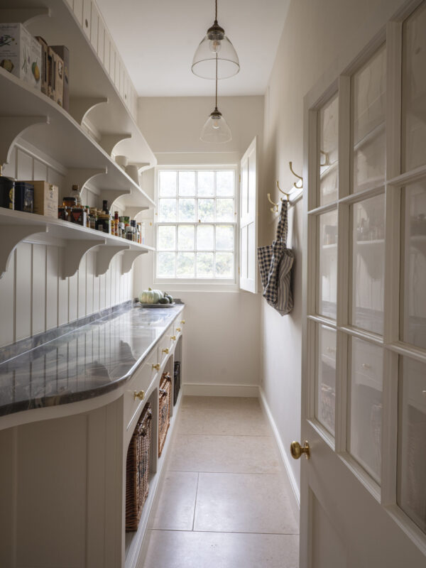 A walk in pantry with wooden open shelves stocked with ingredients