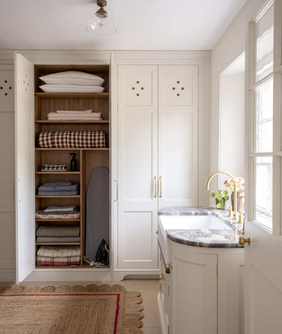 Tall bespoke laundry room storage cabinet with Butler's sink under the window