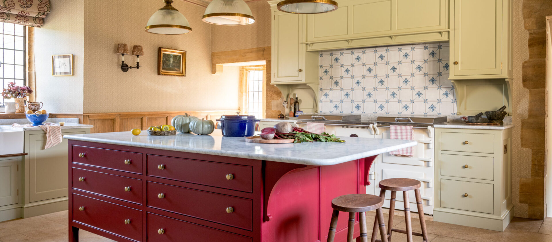 The hand-painted red kitchen island with marble worktop and two bar stools