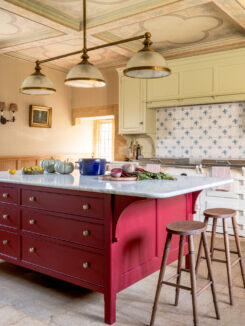 The hand-painted red kitchen island with marble worktop and two bar stools