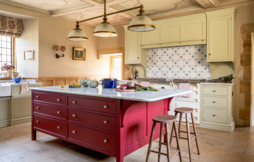The hand-painted red kitchen island with marble worktop and two bar stools