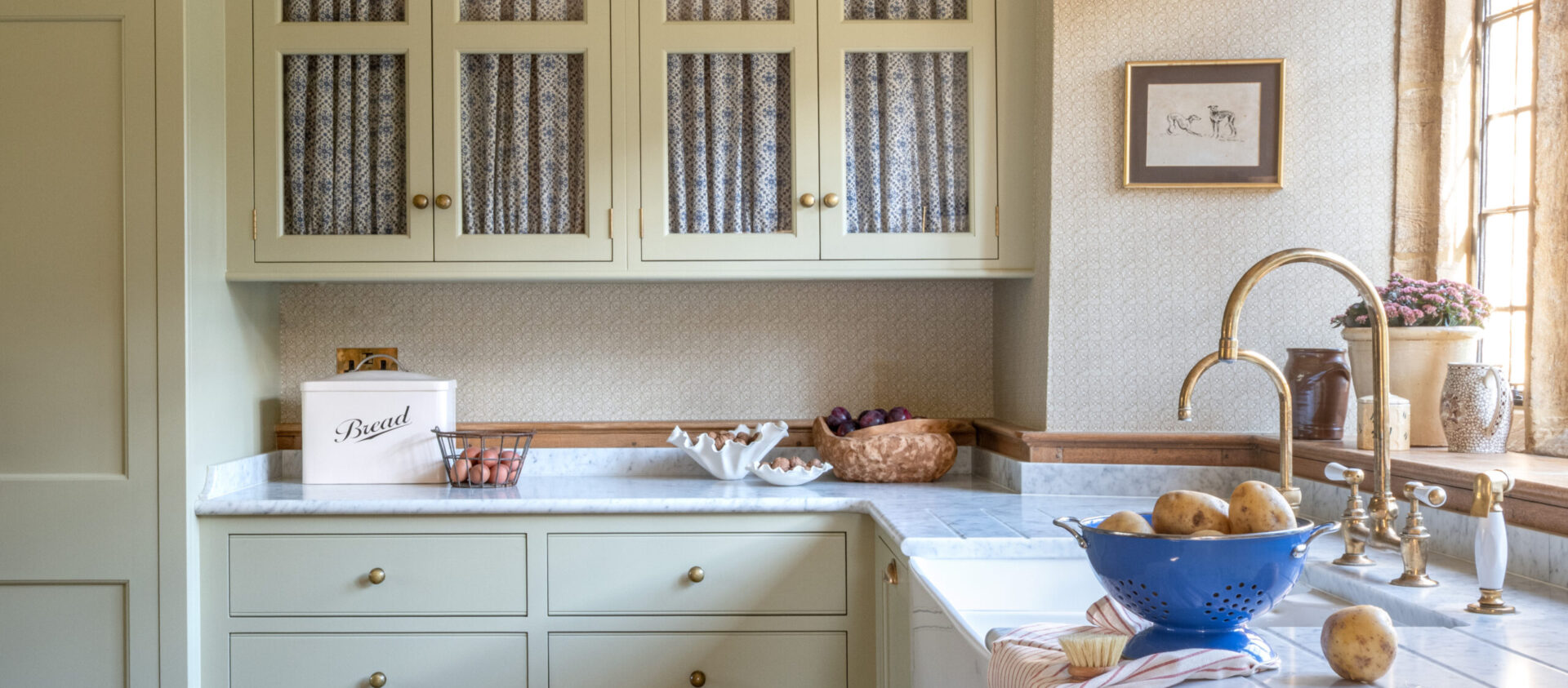 Bespoke cabinetry design for a listed Manor House with hand painted glazed cabinets and Butler sink under a stone mullion window