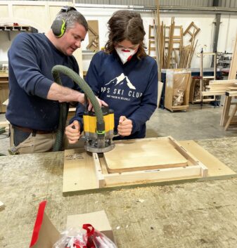 A student being shown how to sand their wooden chopping board in the Guild Anderson workshop