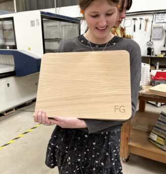 A student with their finished wooden chopping board in the Guild Anderson workshop