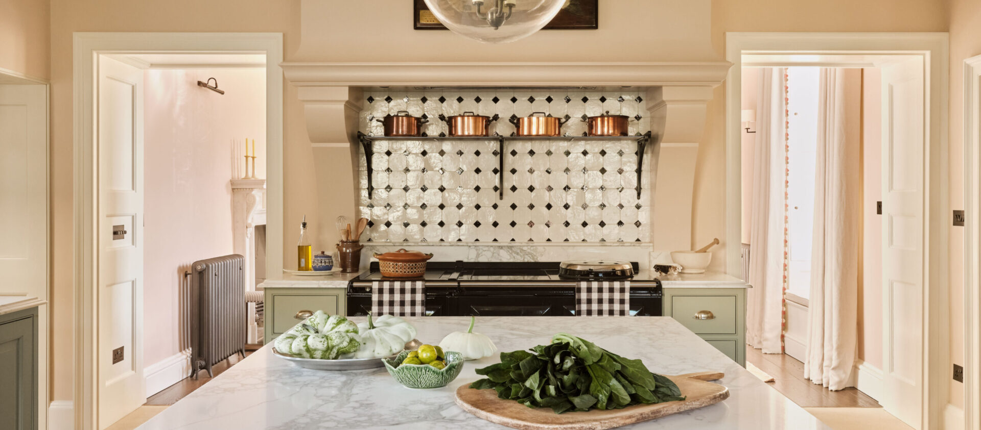 The Old Rectory period kitchen in the Cotswolds with large kitchen island and Aga range cooker with copper saucepans