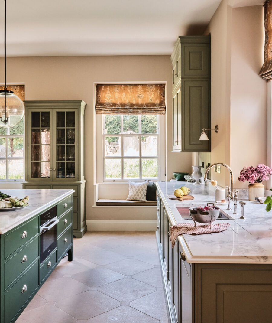 The Old Rectory kitchen in the Cotswolds with large green painted kitchen island looks out on to the neighbouring church yard The Old Rectory kitchen in the Cotswolds with large green painted kitchen island looks out on to the neighbouring church yard